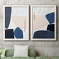 Set of two white barnwood framed canvas prints depicting a coordinated art pair of large navy cream and beige organic geometric shapes rendered as minimalist color-block abstracts above a sofa in a modern living room.