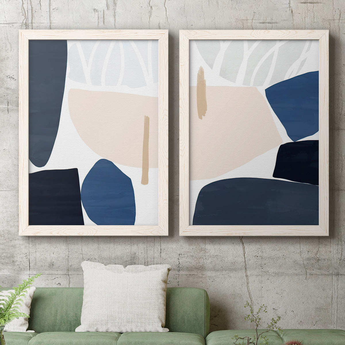 Set of two white barnwood framed canvas prints depicting a coordinated art pair of large navy cream and beige organic geometric shapes rendered as minimalist color-block abstracts above a sofa in a modern living room.
