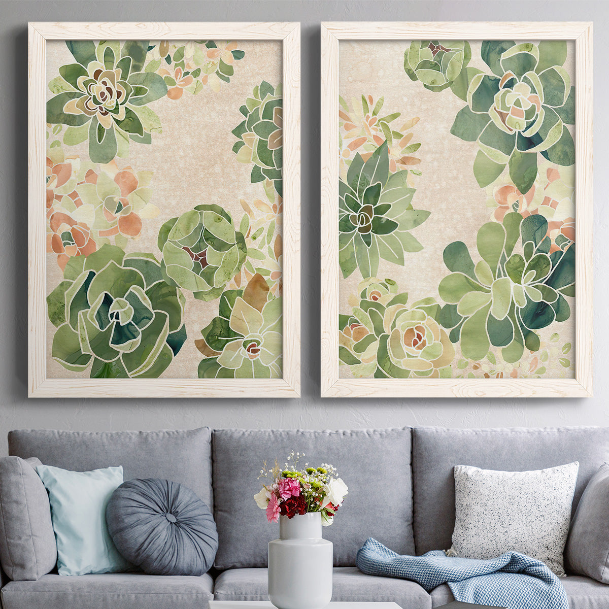 Set of two white barnwood framed canvas prints depicting paired decorative botanical pattern prints with green rosettes, peach blossoms, and mosaic-like outlines above a sofa in a contemporary living room.