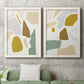 Set of two white barnwood framed canvas prints depicting a coordinated art pair of soft mustard sage gray and white irregular shapes rendered as pastel geometric abstracts above a sofa in a modern living room.