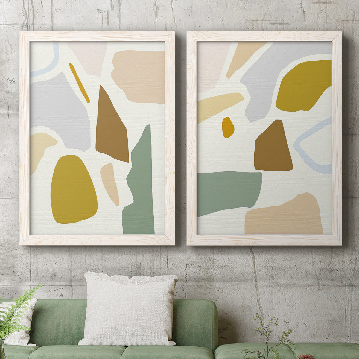 Set of two white barnwood framed canvas prints depicting a coordinated art pair of soft mustard sage gray and white irregular shapes rendered as pastel geometric abstracts above a sofa in a modern living room.