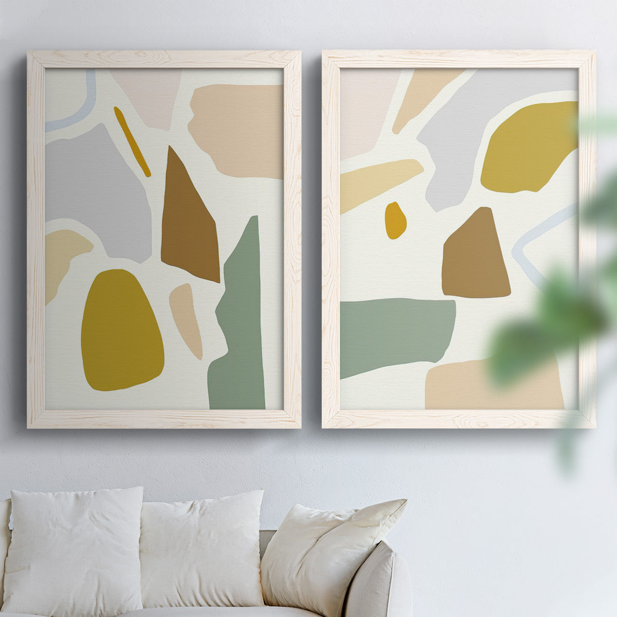 Set of two white barnwood framed canvas prints depicting rounded color patches, thin white boundaries, and airy cream grounds arranged across two complementary compositions above a sofa in a bright living space.
