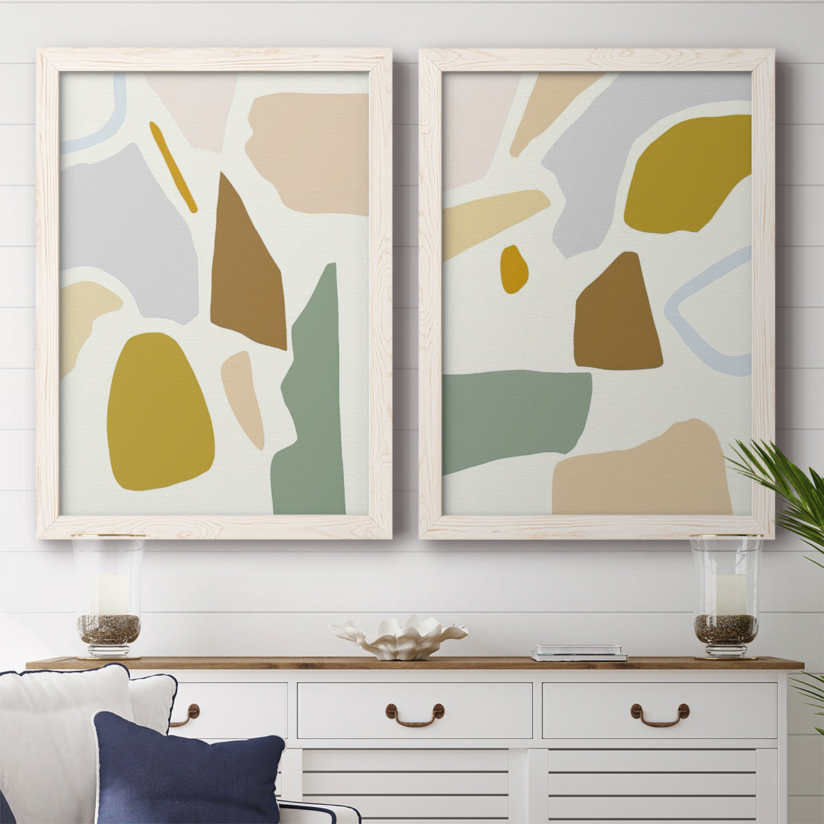 Set of two white barnwood framed canvas prints depicting a coordinated art pair of soft mustard sage gray and white irregular shapes rendered as pastel geometric abstracts above a dining room sideboard.
