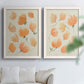 Set of two white barnwood framed canvas prints depicting soft petals, thin black stems, and warm cream backgrounds arranged across two complementary compositions above a sofa in a bright living space.