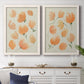 Set of two white barnwood framed canvas prints depicting a coordinated art pair of loose peach-orange tulip-like blossoms rendered as airy watercolor floral paintings above a dining room sideboard.