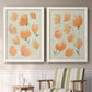 Set of two white barnwood framed canvas prints depicting two airy watercolor floral paintings featuring loose peach-orange tulip-like blossoms above a sideboard in a cozy sitting room.