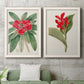 Set of two white barnwood framed canvas prints depicting a coordinated art pair of vivid tropical flowering plants rendered as antique botanical plate illustrations above a sofa in a modern living room.