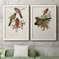 Set of two white barnwood framed canvas prints depicting a coordinated art pair of colorful tropical birds perched on leafy branches rendered as vintage ornithological illustrations above a sofa in a modern living room.