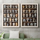 Set of two white barnwood framed canvas prints depicting a coordinated art pair of shelves filled with wooden hat forms rendered as fashion-object photography above a sofa in a modern living room.