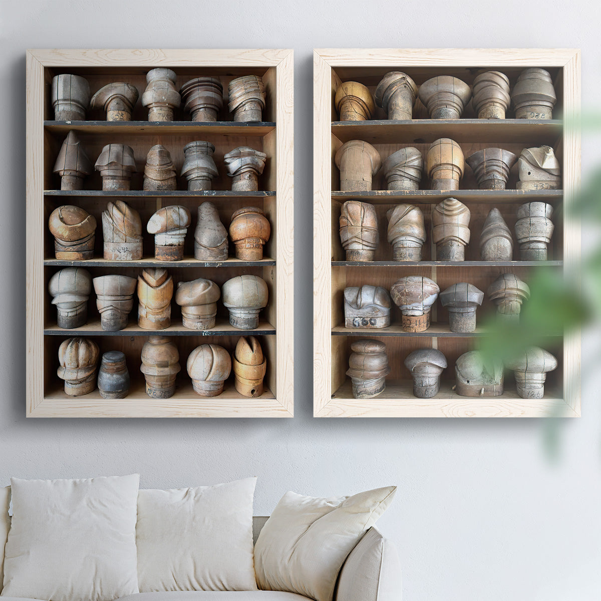 Set of two white barnwood framed canvas prints depicting rows of carved hat blocks, warm wood tones, and workshop shelving arranged across two complementary compositions above a sofa in a bright living space.