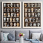 Set of two white barnwood framed canvas prints depicting paired fashion-object photography with rows of carved hat blocks, warm wood tones, and workshop shelving above a sofa in a contemporary living room.