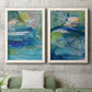 Set of two white barnwood framed canvas prints depicting a coordinated art pair of layered blue teal green and yellow painterly fields rendered as energetic mixed-media abstracts above a sofa in a modern living room.