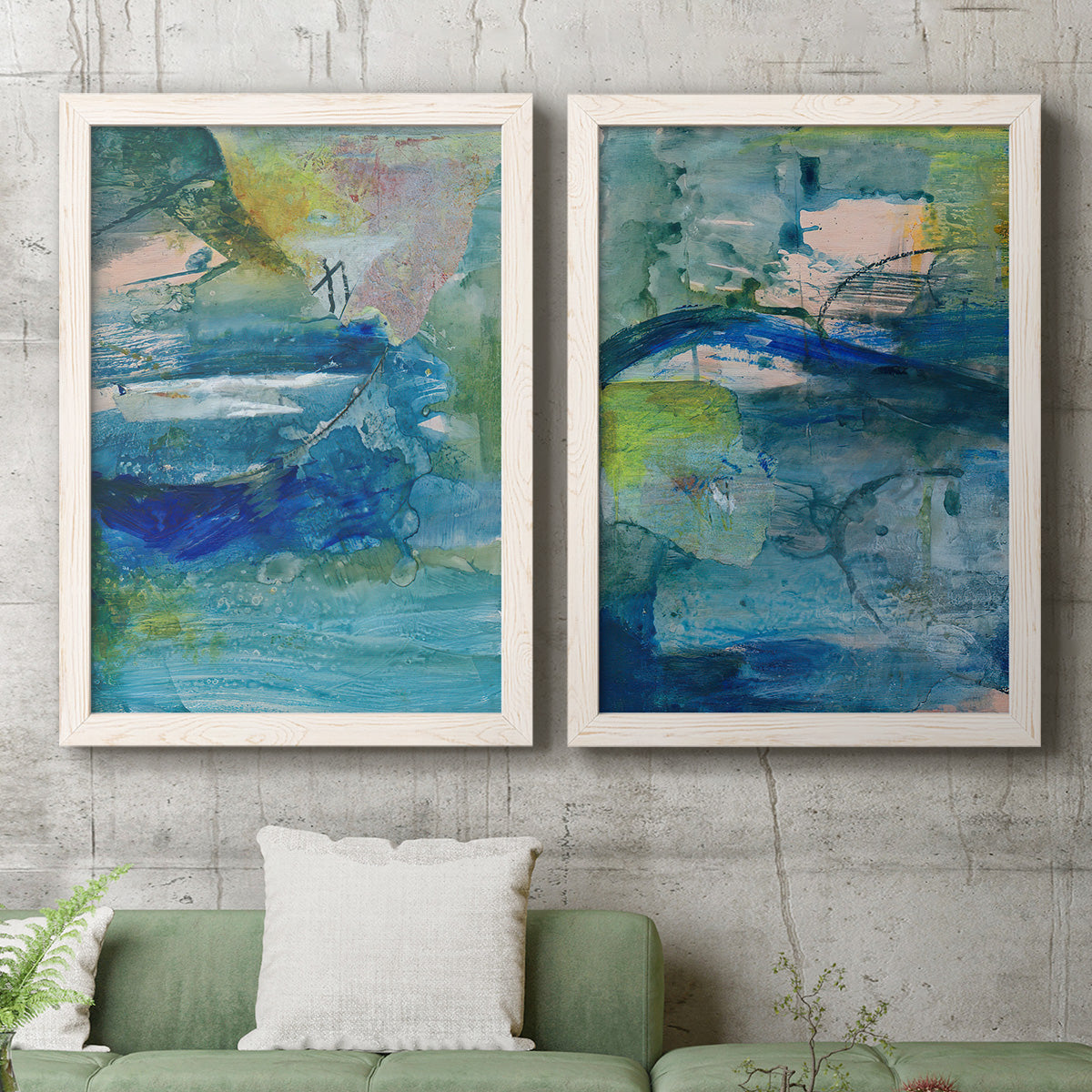 Set of two white barnwood framed canvas prints depicting a coordinated art pair of layered blue teal green and yellow painterly fields rendered as energetic mixed-media abstracts above a sofa in a modern living room.