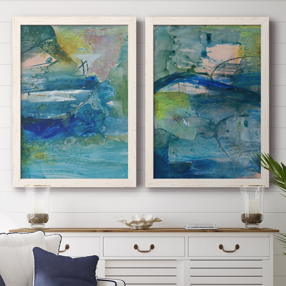 Set of two white barnwood framed canvas prints depicting a coordinated art pair of layered blue teal green and yellow painterly fields rendered as energetic mixed-media abstracts above a dining room sideboard.