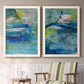 Set of two white barnwood framed canvas prints depicting two energetic mixed-media abstracts featuring layered blue teal green and yellow painterly fields above a sideboard in a cozy sitting room.