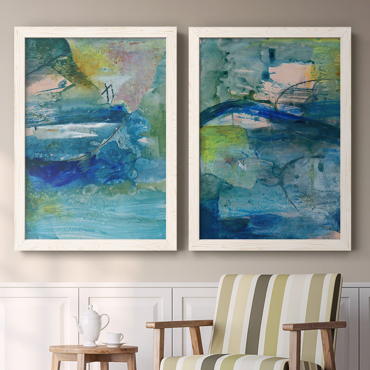 Set of two white barnwood framed canvas prints depicting two energetic mixed-media abstracts featuring layered blue teal green and yellow painterly fields above a sideboard in a cozy sitting room.