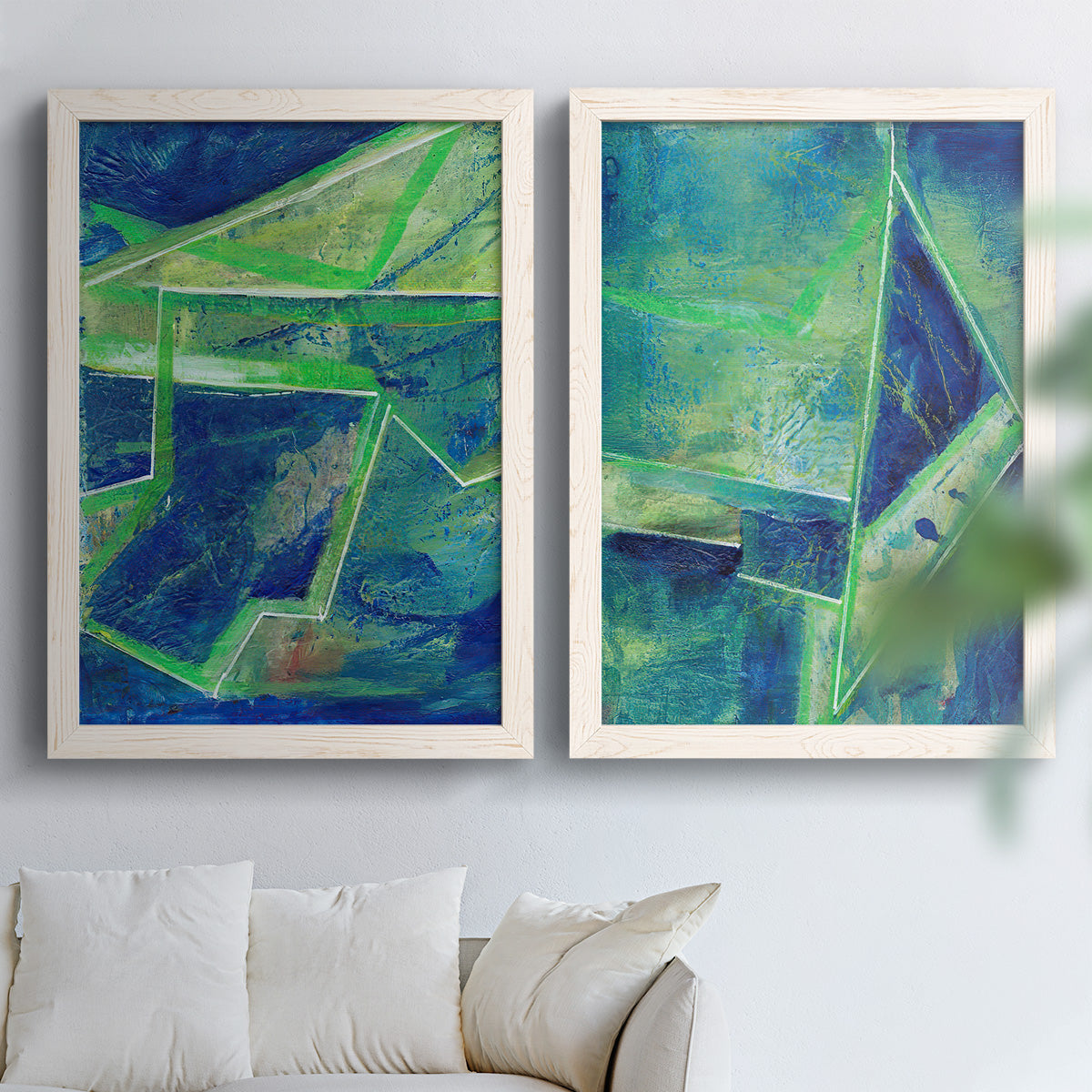 Set of two white barnwood framed canvas prints depicting deep cobalt fields, bright green edges, and layered linear facets arranged across two complementary compositions above a sofa in a bright living space.