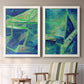 Set of two white barnwood framed canvas prints depicting two textured geometric abstracts featuring interlocking blue and green angular forms above a sideboard in a cozy sitting room.