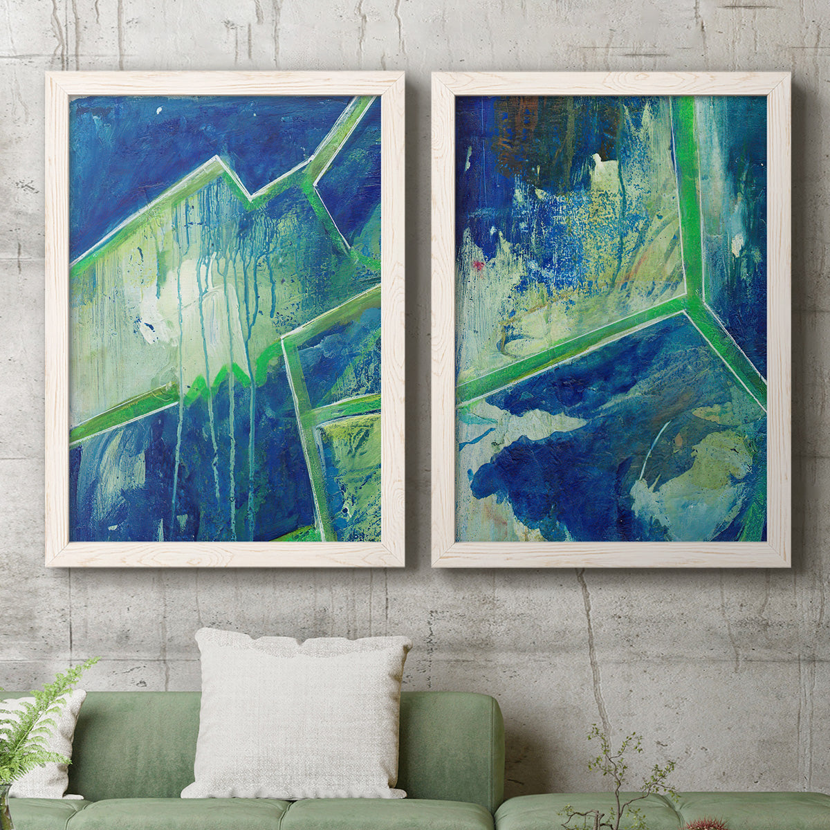 Set of two white barnwood framed canvas prints depicting a coordinated art pair of interlocking blue and green angular forms rendered as textured geometric abstracts above a sofa in a modern living room.