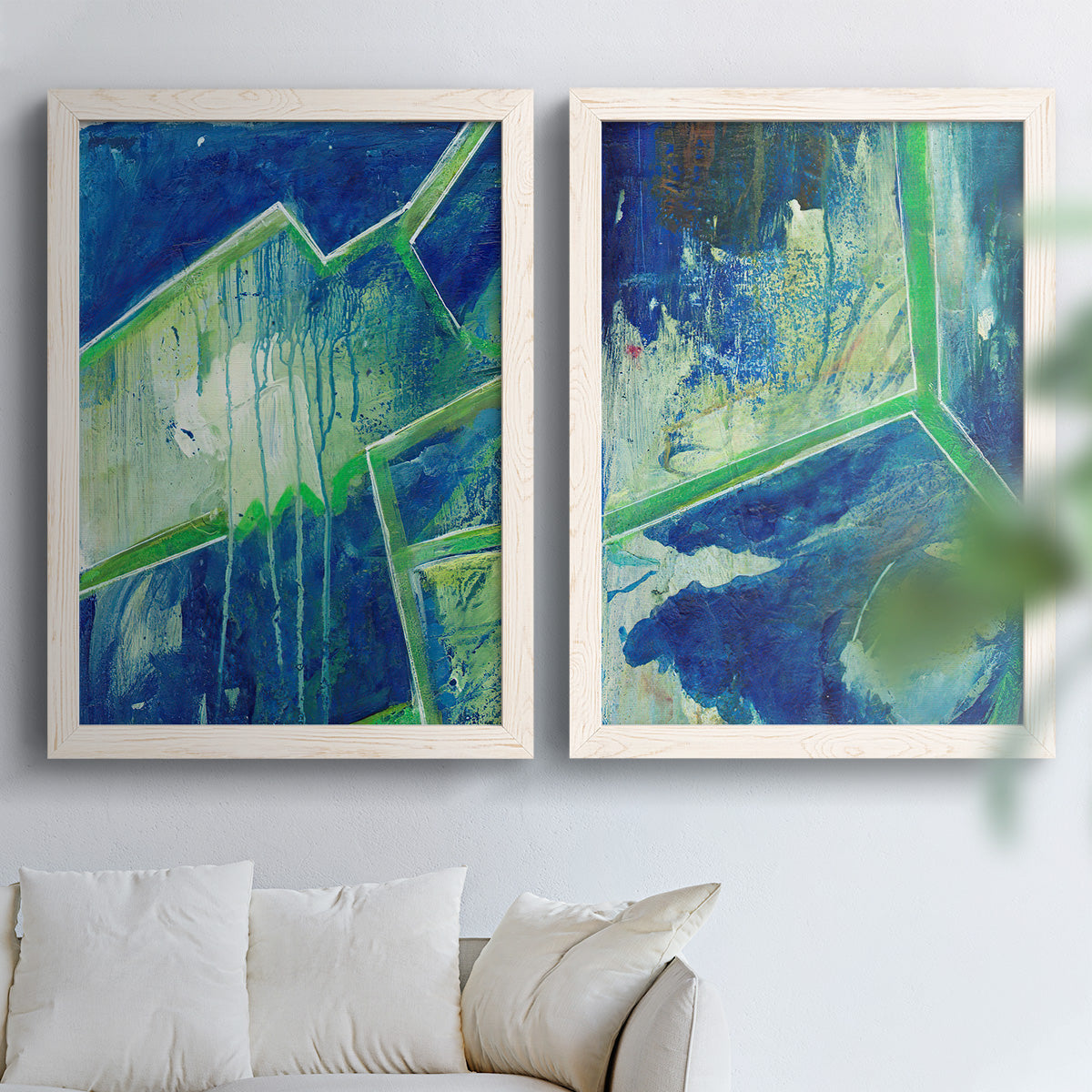 Set of two white barnwood framed canvas prints depicting deep cobalt fields, bright green edges, and layered linear facets arranged across two complementary compositions above a sofa in a bright living space.