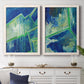 Set of two white barnwood framed canvas prints depicting a coordinated art pair of interlocking blue and green angular forms rendered as textured geometric abstracts above a dining room sideboard.