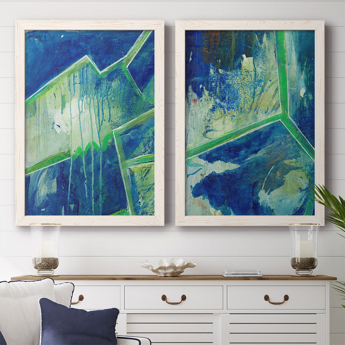 Set of two white barnwood framed canvas prints depicting a coordinated art pair of interlocking blue and green angular forms rendered as textured geometric abstracts above a dining room sideboard.
