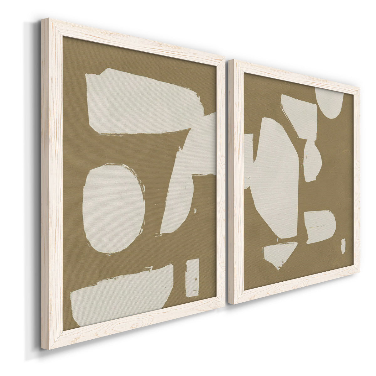 Angled view of a set of two white barnwood framed canvas prints featuring two bold minimalist shape abstracts featuring irregular white cutout-like shapes on taupe grounds.