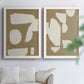 Set of two white barnwood framed canvas prints depicting flat blocky forms, rough painted edges, and strong negative space arranged across two complementary compositions above a sofa in a bright living space.