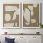 Set of two white barnwood framed canvas prints depicting a coordinated art pair of irregular white cutout-like shapes on taupe grounds rendered as bold minimalist shape abstracts above a dining room sideboard.