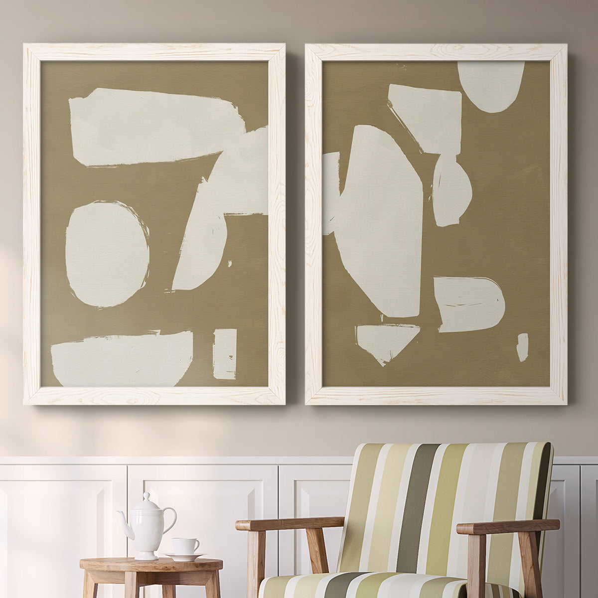 Set of two white barnwood framed canvas prints depicting two bold minimalist shape abstracts featuring irregular white cutout-like shapes on taupe grounds above a sideboard in a cozy sitting room.