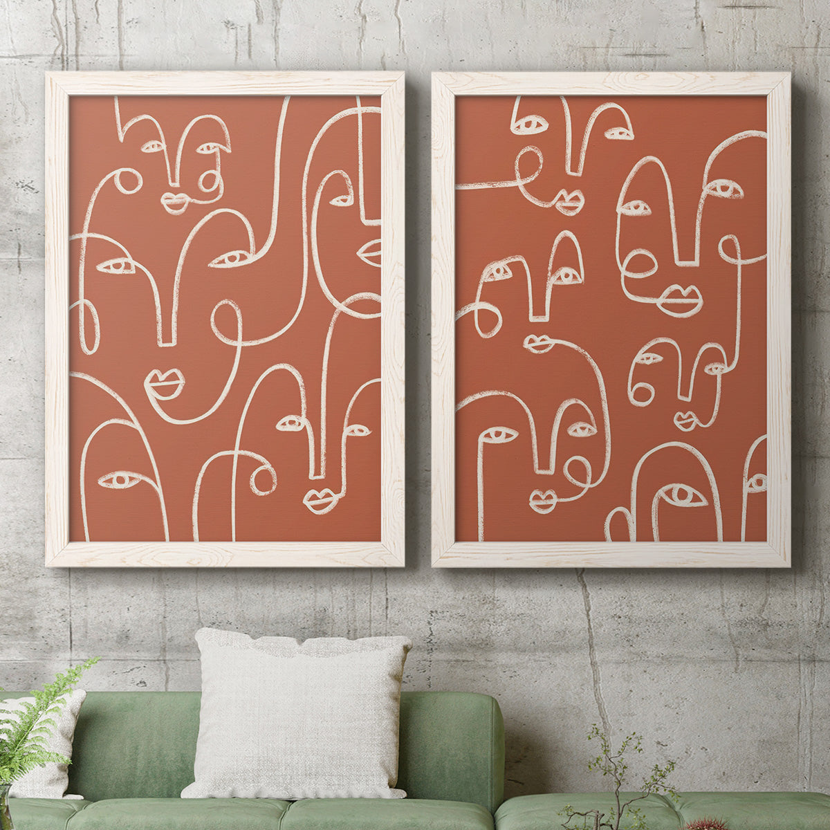 Set of two white barnwood framed canvas prints depicting a coordinated art pair of many continuous-line faces across terracotta grounds rendered as graphic portrait patterns above a sofa in a modern living room.