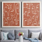 Set of two white barnwood framed canvas prints depicting paired graphic portrait patterns with white outlined features, repeated profiles, and playful clustered expressions above a sofa in a contemporary living room.
