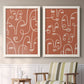 Set of two white barnwood framed canvas prints depicting two graphic portrait patterns featuring many continuous-line faces across terracotta grounds above a sideboard in a cozy sitting room.