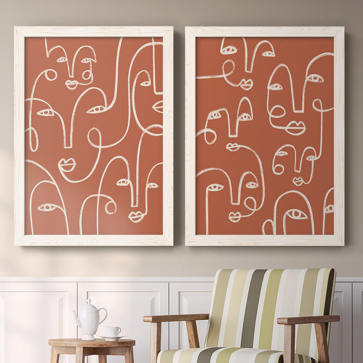Set of two white barnwood framed canvas prints depicting two graphic portrait patterns featuring many continuous-line faces across terracotta grounds above a sideboard in a cozy sitting room.