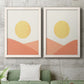 Set of two white barnwood framed canvas prints depicting a coordinated art pair of yellow suns rising over terracotta geometric hills rendered as minimalist boho landscapes above a sofa in a modern living room.
