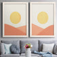 Set of two white barnwood framed canvas prints depicting paired minimalist boho landscapes with flat semicircles, warm peach slopes, and clean cream skies above a sofa in a contemporary living room.