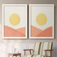 Set of two white barnwood framed canvas prints depicting two minimalist boho landscapes featuring yellow suns rising over terracotta geometric hills above a sideboard in a cozy sitting room.