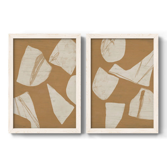Set of two white barnwood framed canvas prints featuring two minimalist collage abstracts featuring irregular cream paper-like shapes on warm brown.