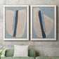 Set of two white barnwood framed canvas prints depicting a coordinated art pair of single navy brush slashes across layered paper-like shapes rendered as minimalist collage-style abstracts above a sofa in a modern living room.