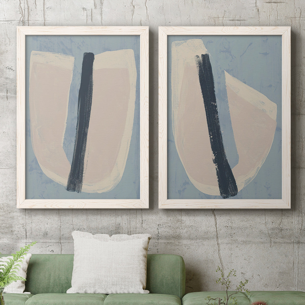 Set of two white barnwood framed canvas prints depicting a coordinated art pair of single navy brush slashes across layered paper-like shapes rendered as minimalist collage-style abstracts above a sofa in a modern living room.