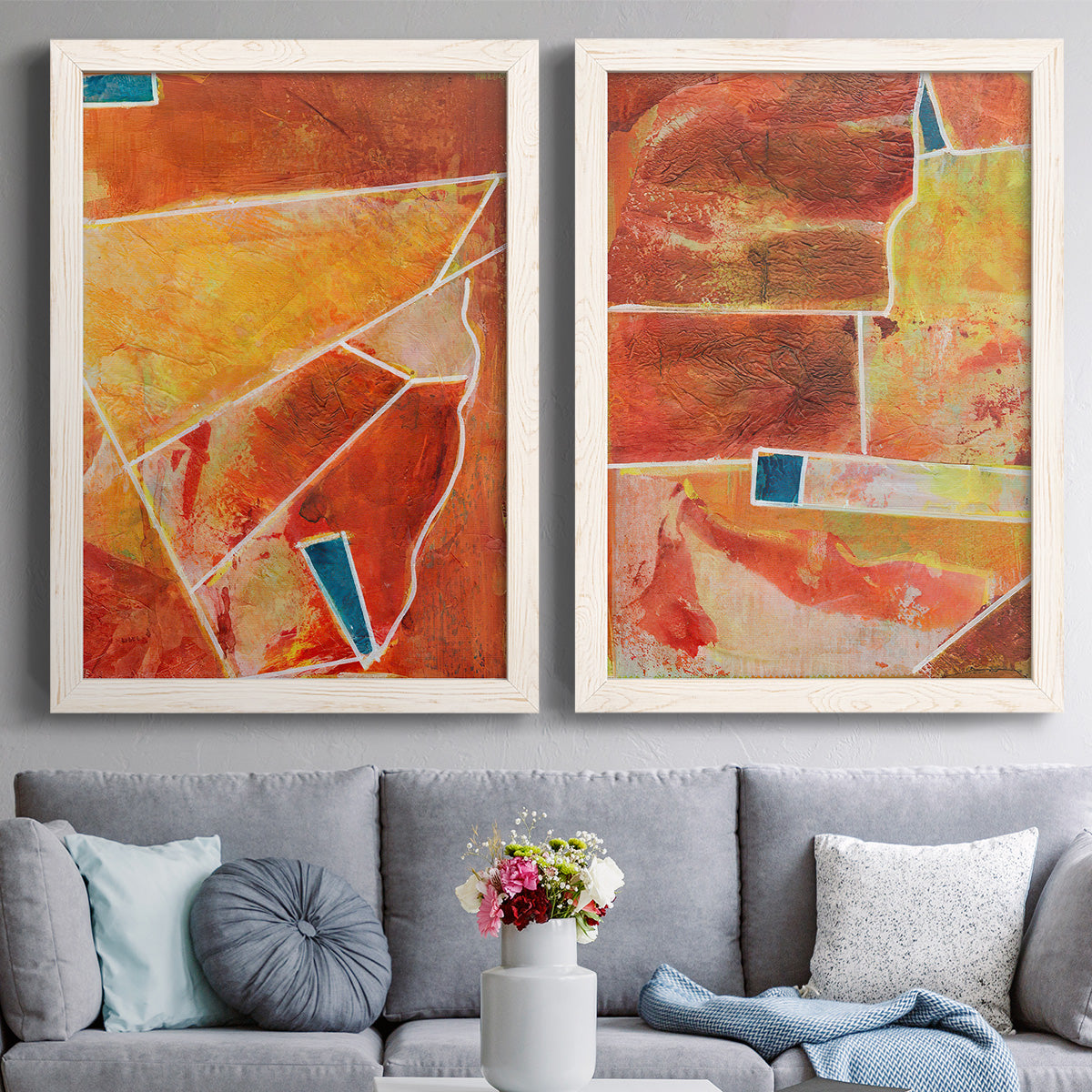 Set of two white barnwood framed canvas prints depicting paired warm geometric abstracts with white dividing lines, small turquoise accents, and layered painted texture above a sofa in a contemporary living room.