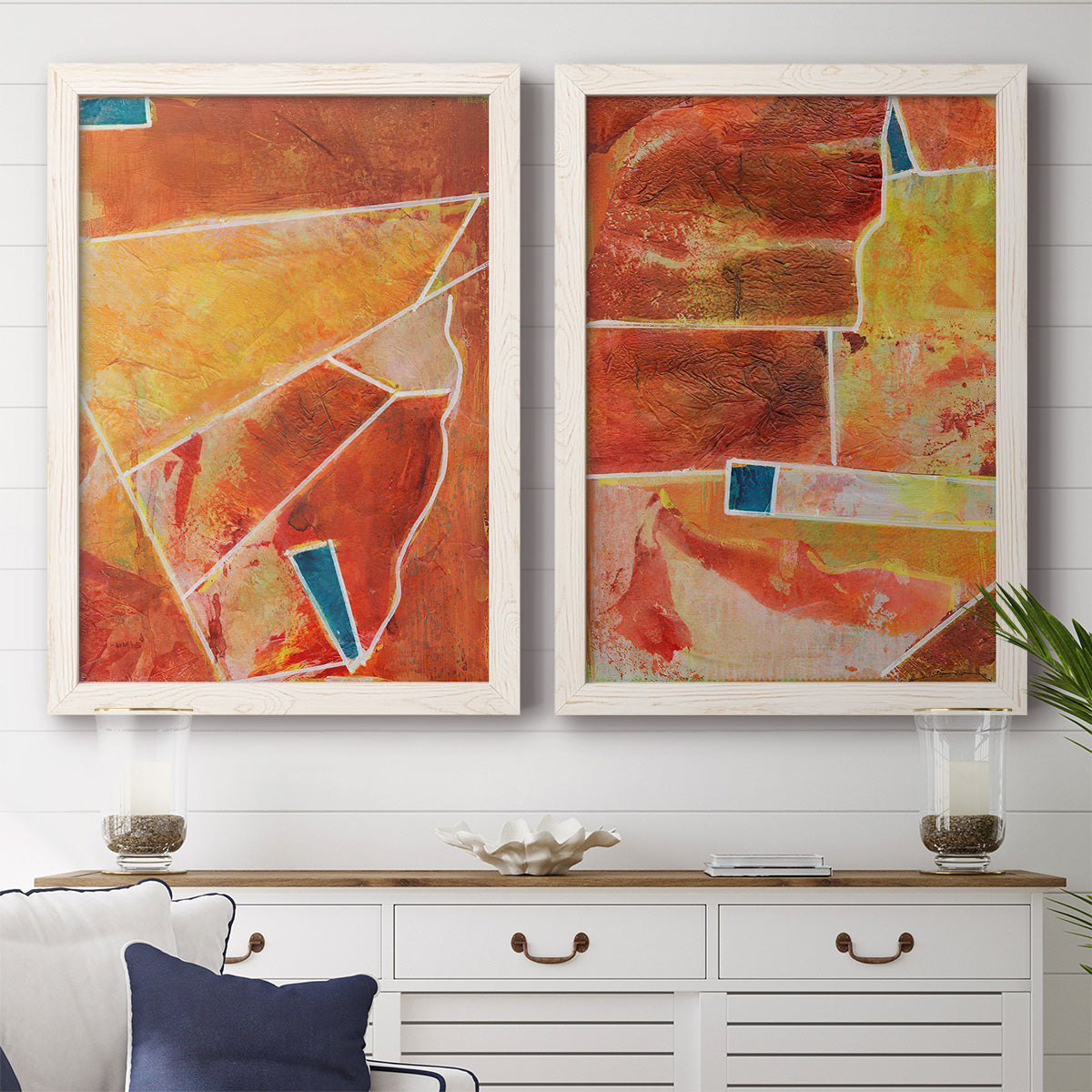 Set of two white barnwood framed canvas prints depicting a coordinated art pair of faceted rust orange and coral geometric fields rendered as warm geometric abstracts above a dining room sideboard.