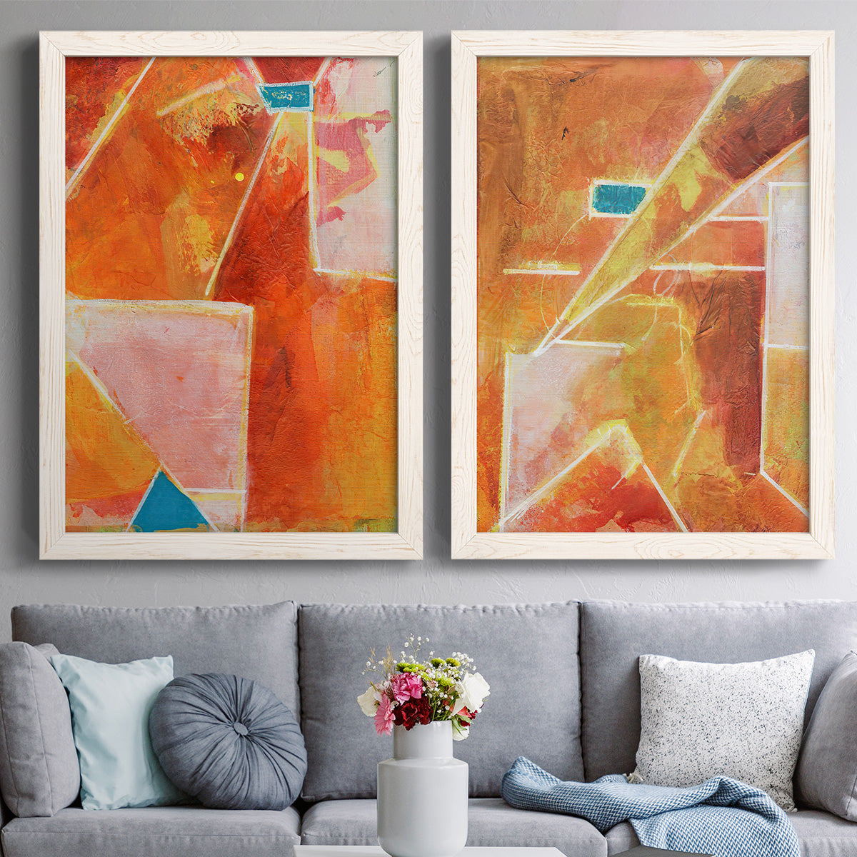 Set of two white barnwood framed canvas prints depicting paired warm geometric abstracts with white dividing lines, small turquoise accents, and layered painted texture above a sofa in a contemporary living room.