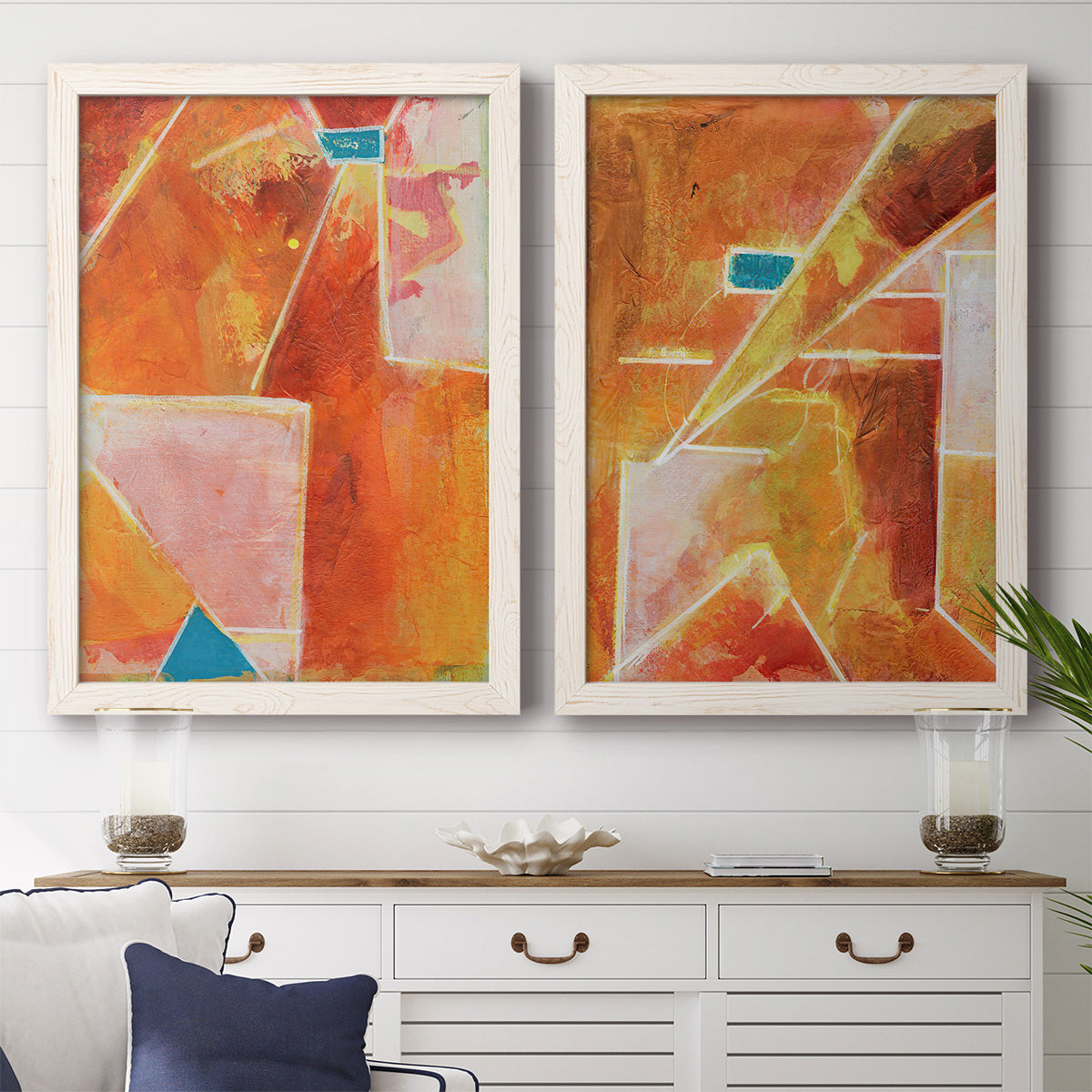 Set of two white barnwood framed canvas prints depicting a coordinated art pair of faceted rust orange and coral geometric fields rendered as warm geometric abstracts above a dining room sideboard.