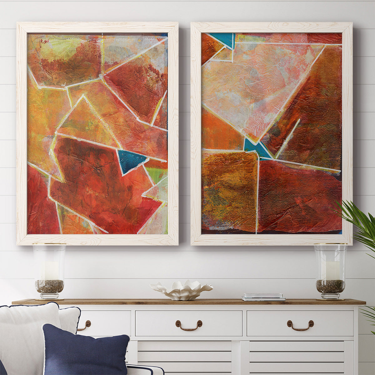 Set of two white barnwood framed canvas prints depicting a coordinated art pair of faceted rust orange and coral geometric fields rendered as warm geometric abstracts above a dining room sideboard.