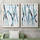 Set of two white barnwood framed canvas prints depicting a coordinated art pair of branching watercolor lines drifting across white rendered as fluid organic abstracts above a sofa in a modern living room.