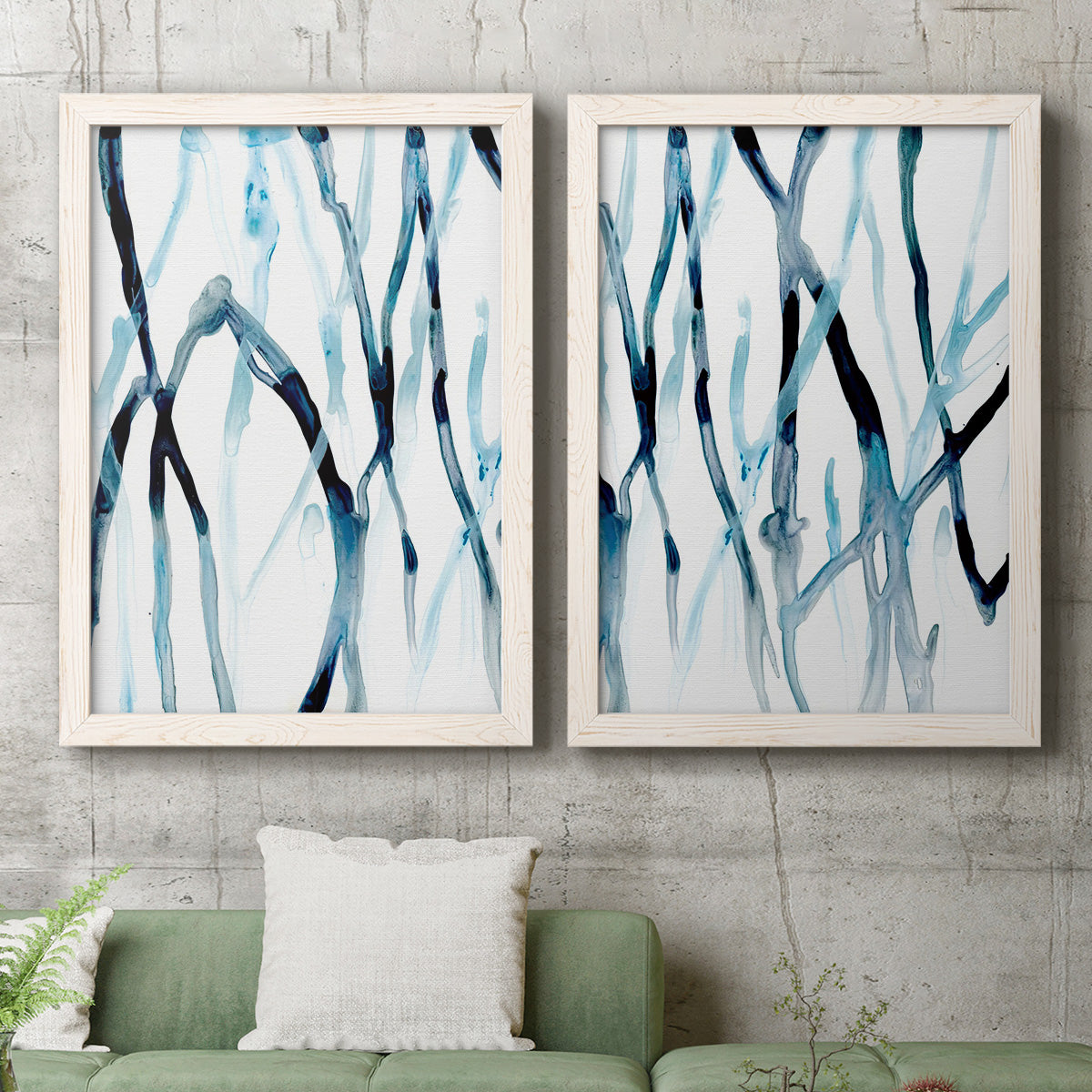 Set of two white barnwood framed canvas prints depicting a coordinated art pair of branching watercolor lines drifting across white rendered as fluid organic abstracts above a sofa in a modern living room.