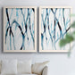 Set of two white barnwood framed canvas prints depicting slender vein-like strokes, transparent overlaps, and open negative space arranged across two complementary compositions above a sofa in a bright living space.