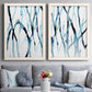 Set of two white barnwood framed canvas prints depicting paired fluid organic abstracts with slender vein-like strokes, transparent overlaps, and open negative space above a sofa in a contemporary living room.