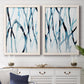 Set of two white barnwood framed canvas prints depicting a coordinated art pair of branching watercolor lines drifting across white rendered as fluid organic abstracts above a dining room sideboard.